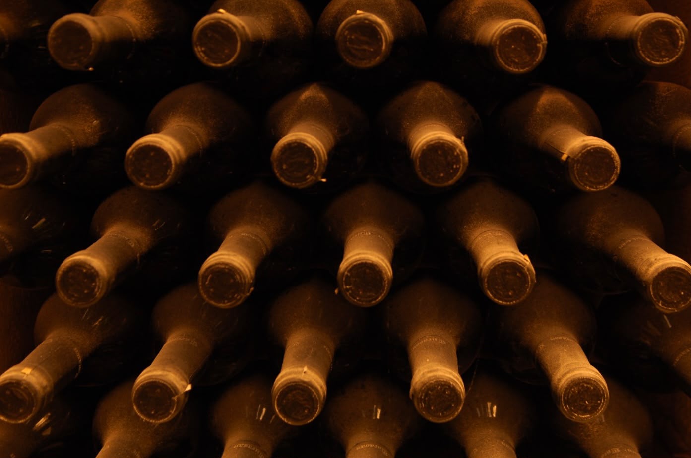 Bottles resting horizontally in cellar niches.
